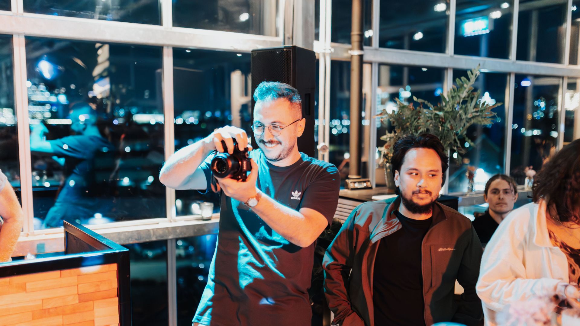 Casual evening team event with a photographer capturing moments indoors.