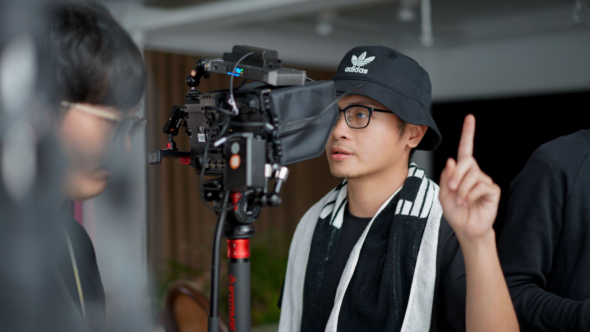 Director focused on managing film equipment and instructing crew indoors.