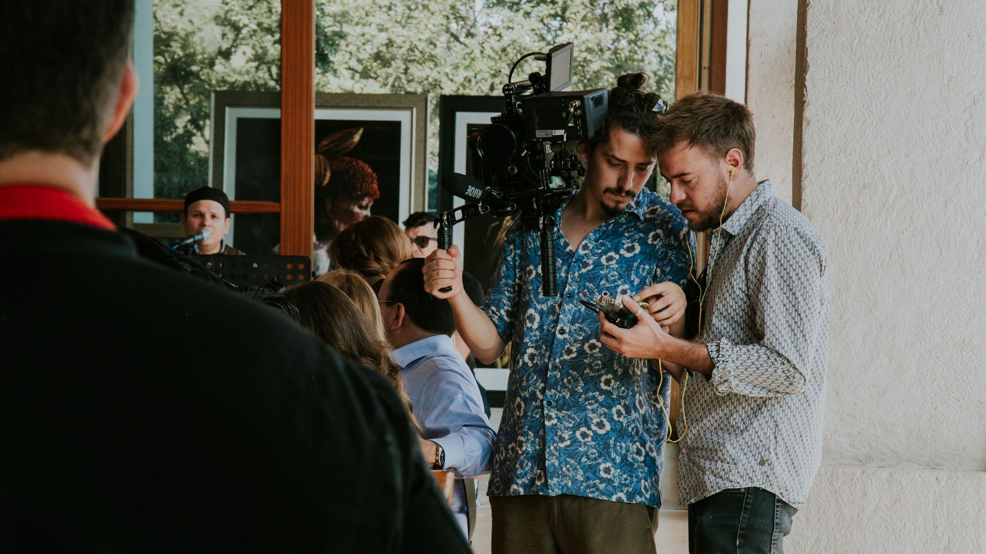 Two videographers inspect camera equipment during an outdoor shoot.
