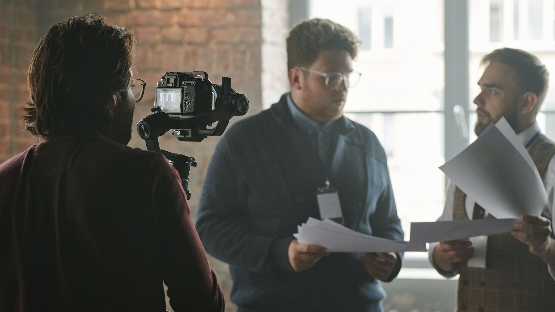 A professional team in a modern office setting being filmed during a business discussion.