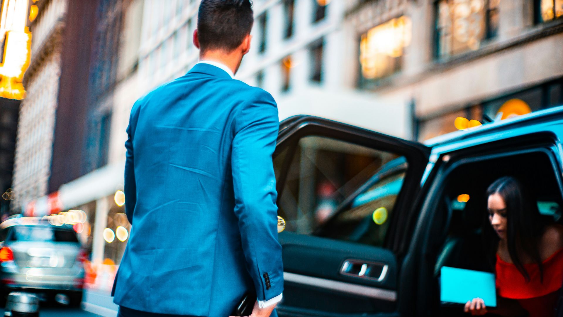 man wearing blue suit standing beside vehicle