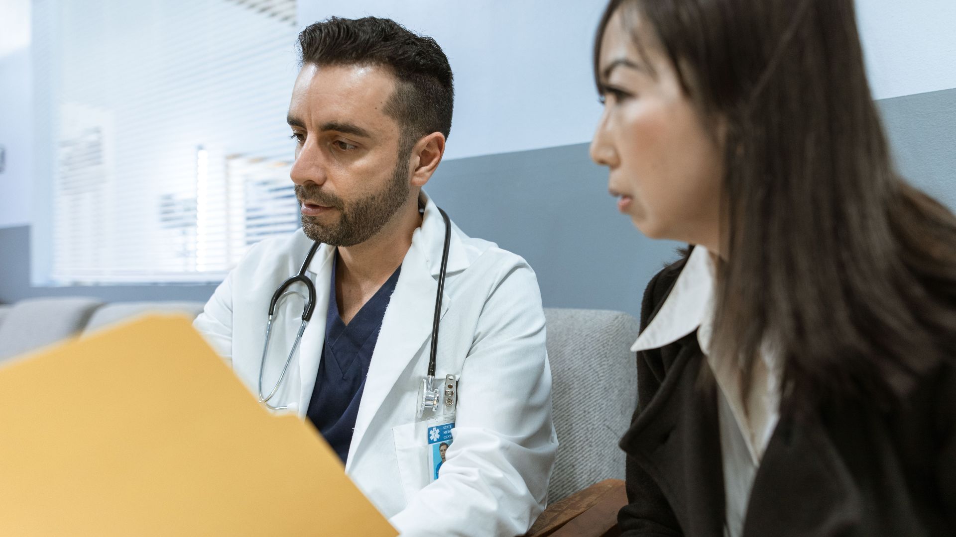 Doctor discusses health records with a patient in a clinical setting.