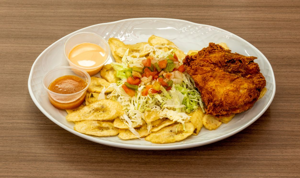 Shutterstock - 2287363777 - Chicken chuco is a traditional Honduran dish originating from the northern coast of Honduras. It consists of fried chicken with plantain slices, topped with sauces, seasonings, and pico de gallo.