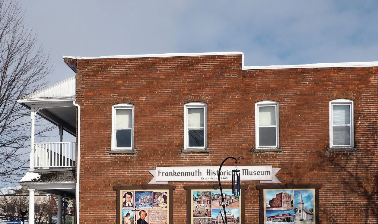 Frankenmuth, MI / USA - February, 7, 2020: central part with Main street on the left and Frankenmuth Historical Museum in front (brick wall with graffiti). Winter day with snow, no people.
