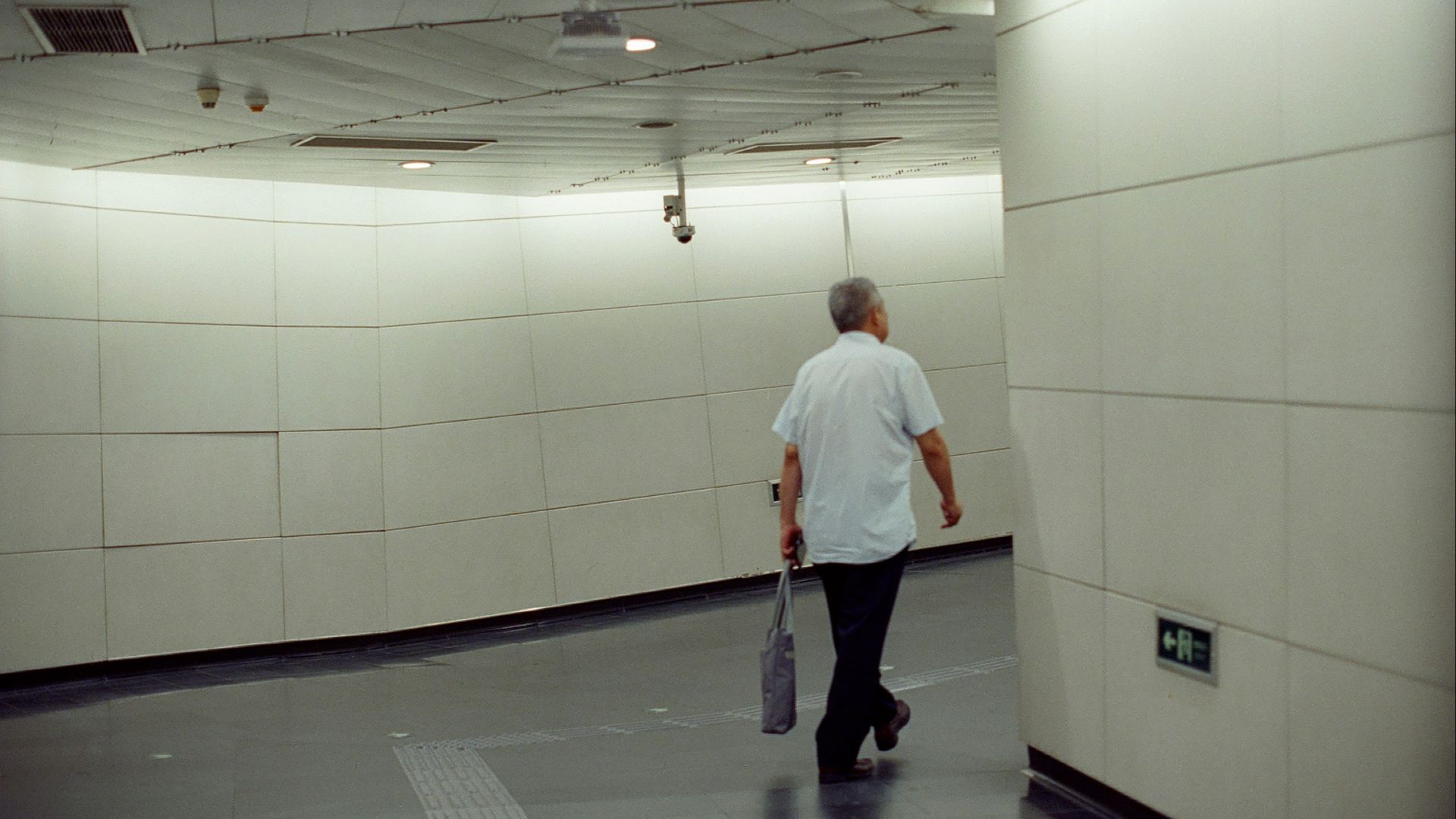 Man walking down a modern, brightly lit hallway