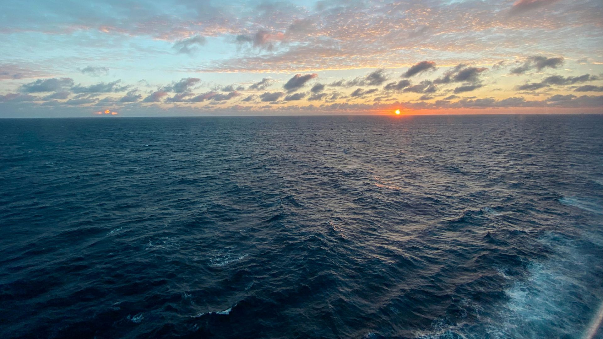 the sun is setting over the ocean as seen from a boat