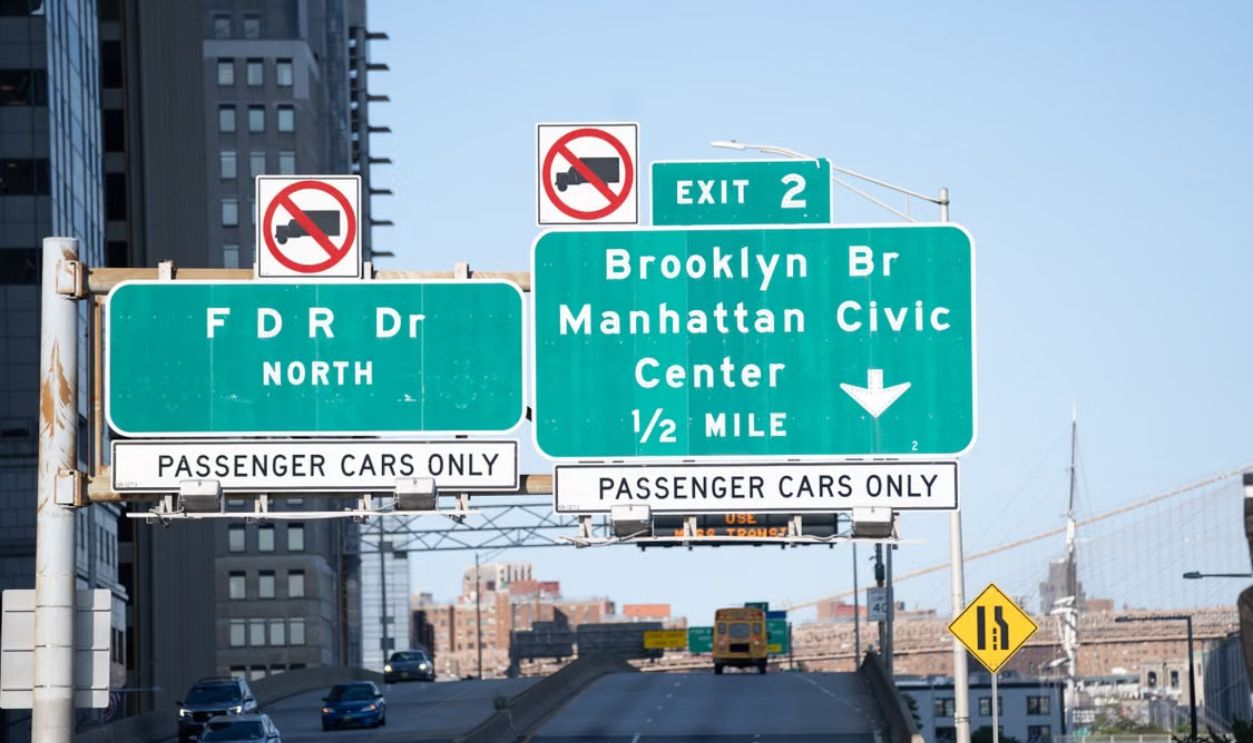 Traffic signs leading to Brooklyn Bridge in New York City on a clear day