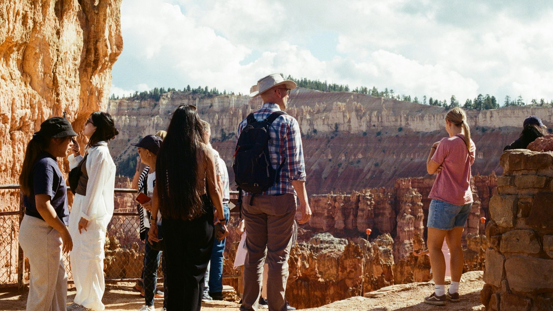 Tourists admire a scenic canyon overlook on a sunny day