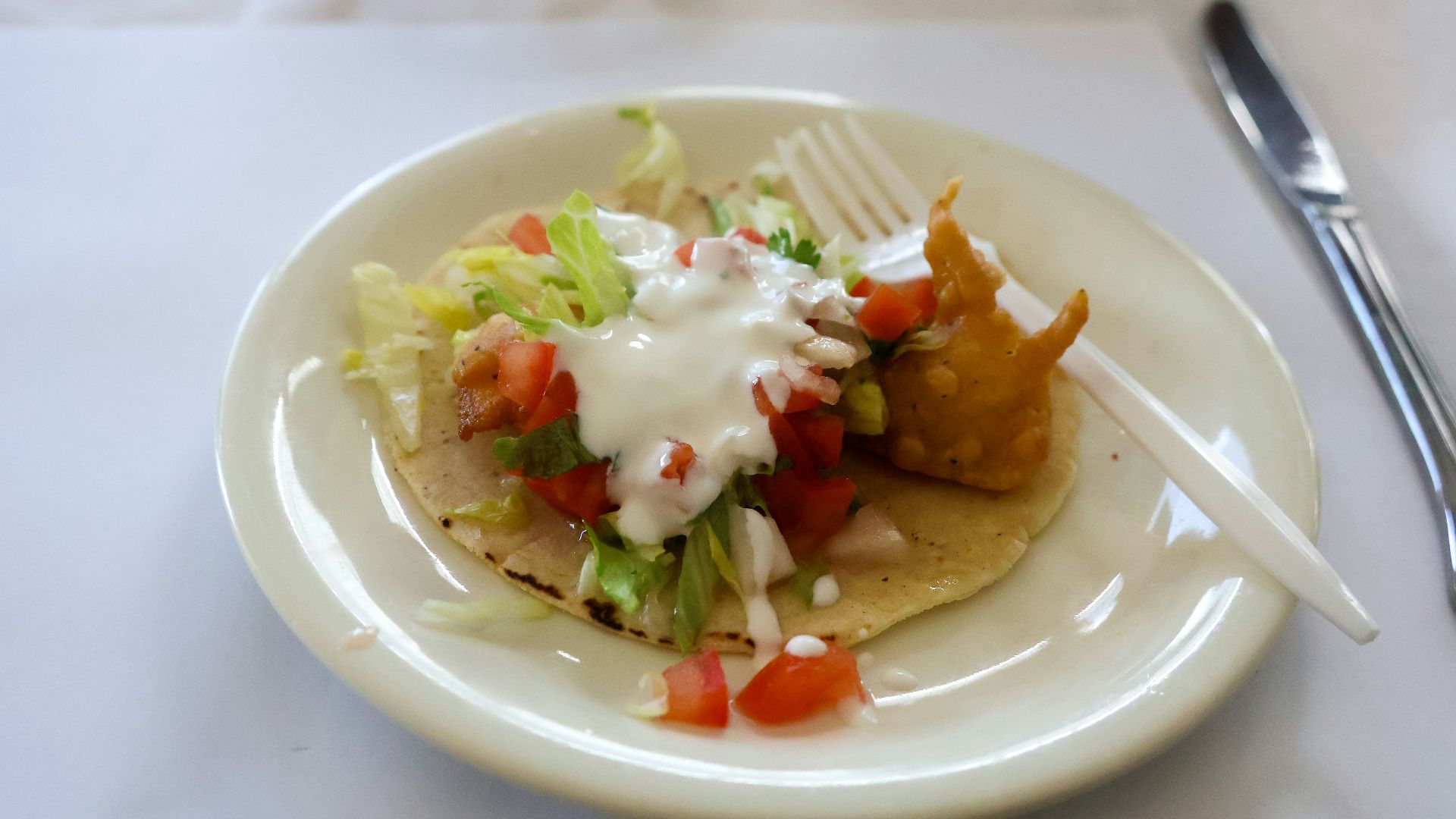 a white plate topped with a taco and a fork