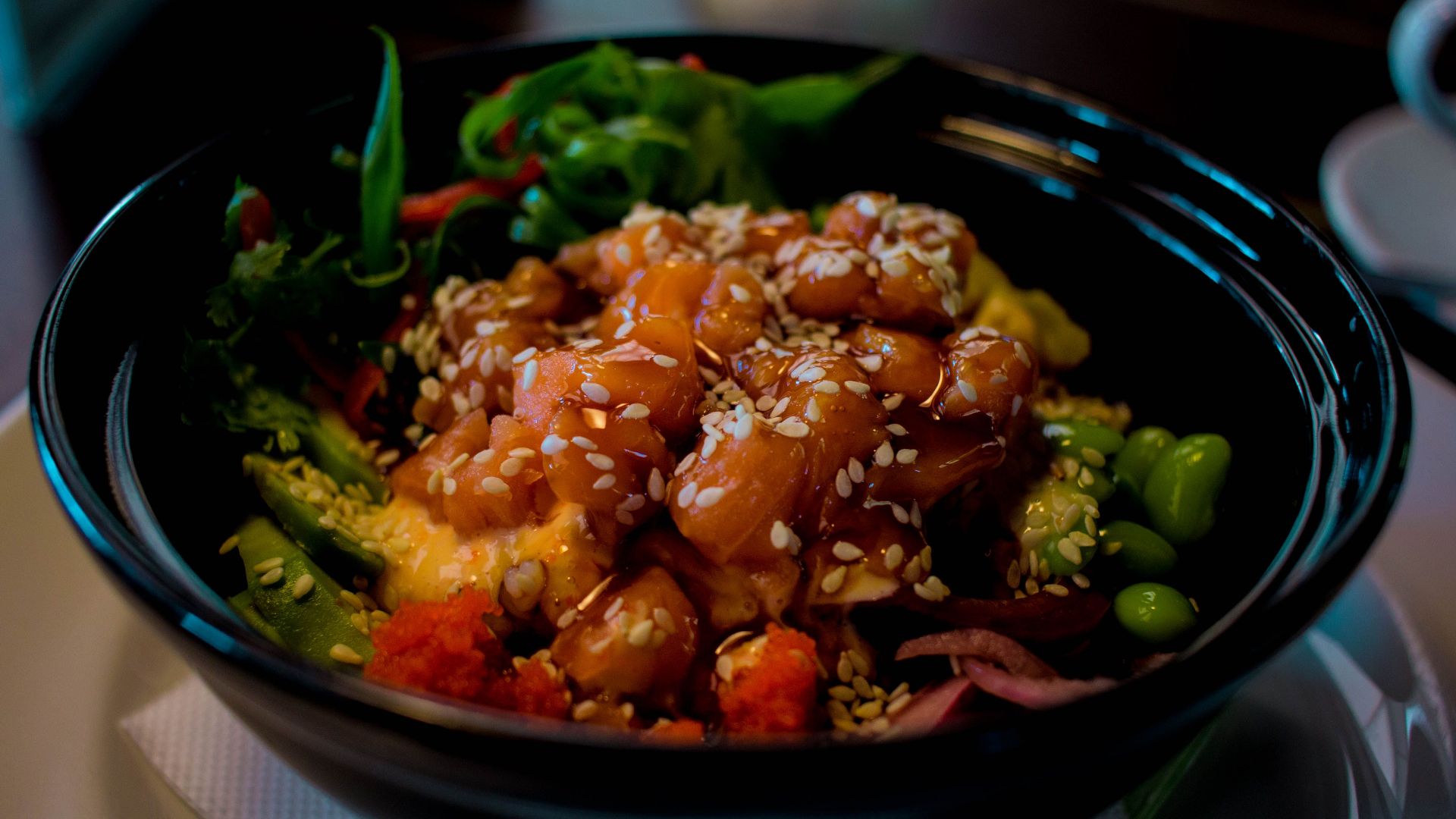 Close-up of a mouthwatering poke bowl with salmon, avocado, and sesame seeds.
