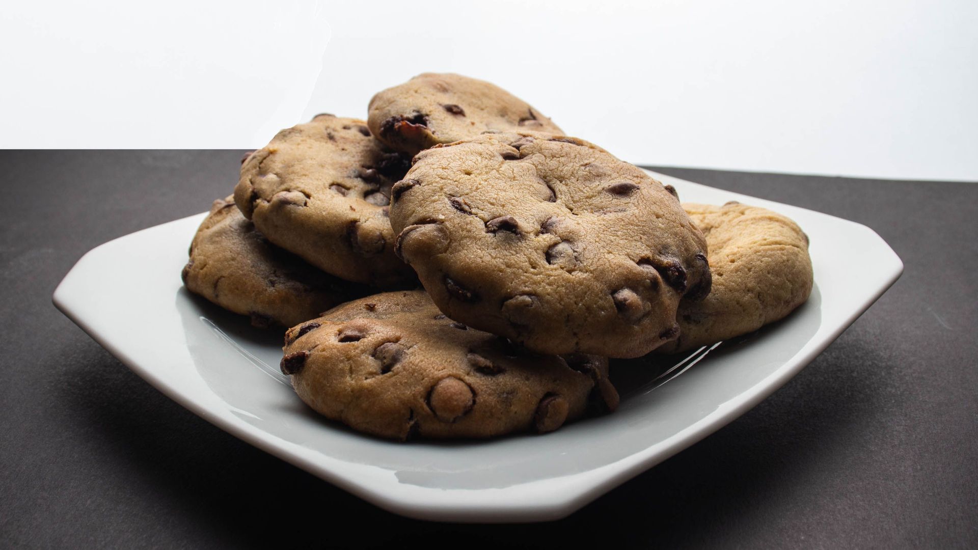 Sumptuous chocolate chip cookies stacked on a white plate, ready to enjoy.