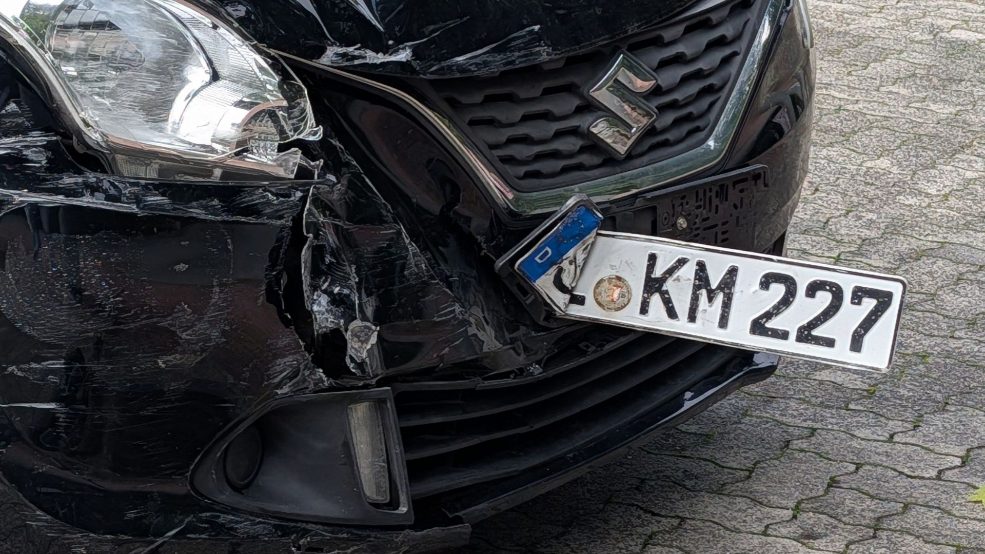 Close-up of a damaged car with a scooter on ground after collision in broad daylight.