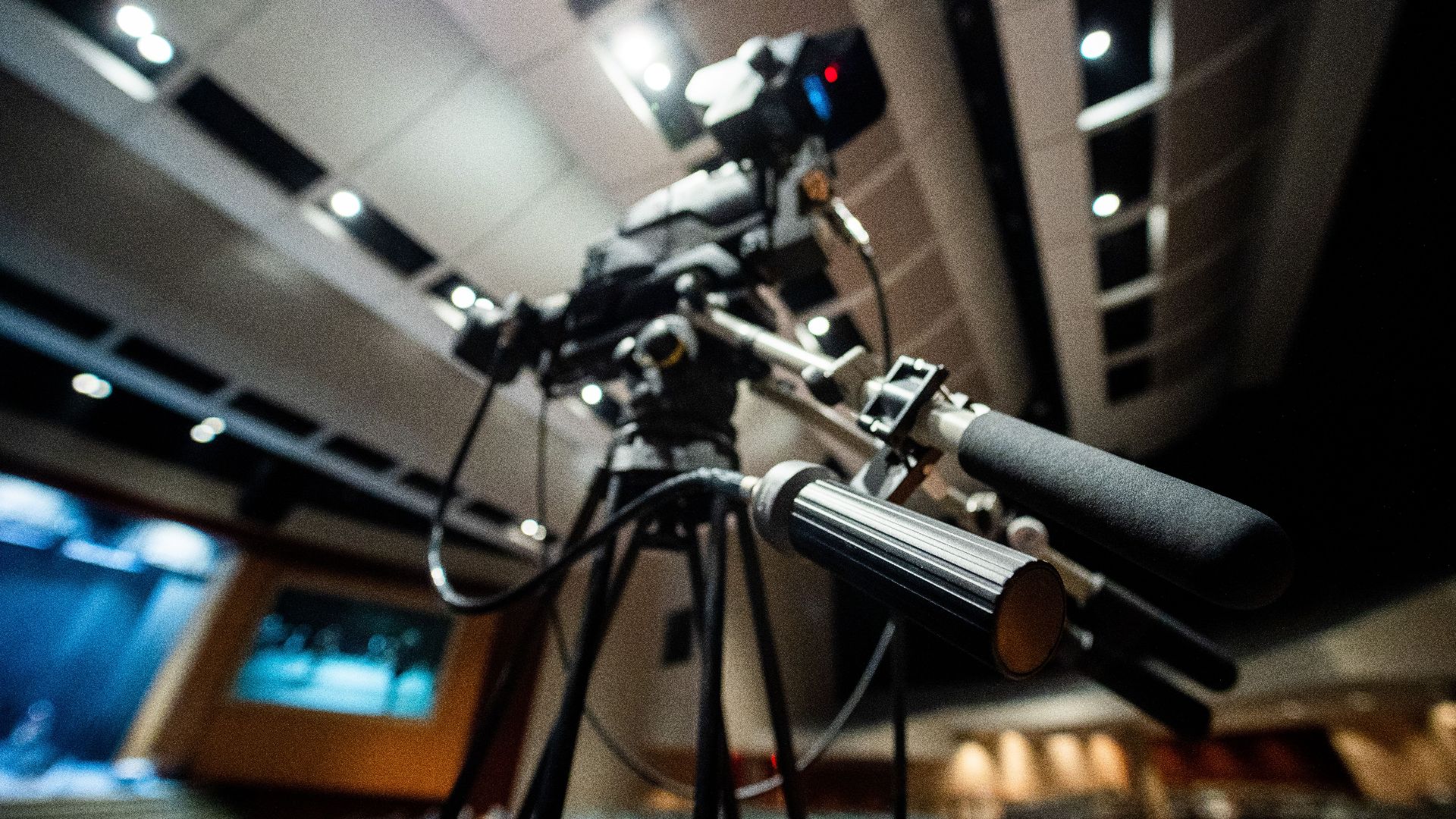 From below of modern professional video camera with wires placed on tripod in studio on blurred background