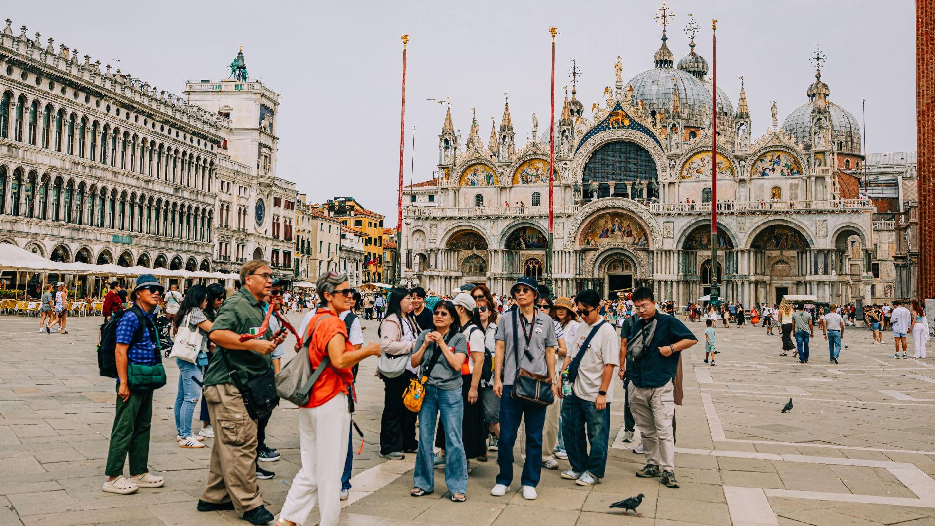 A group of tourists exploring St. Mark's Square in Venice with the Basilica di San Marco in the background.