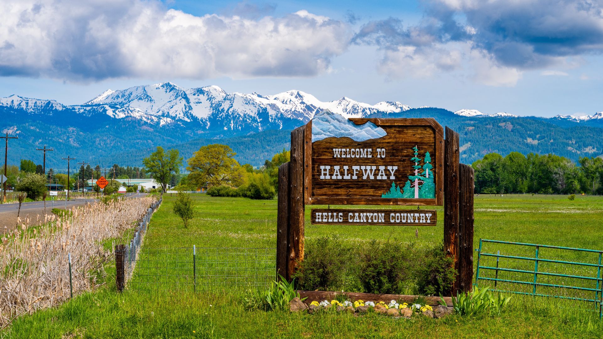Welcome sign to the city of Halfway, Oregon. In the background are the Wallowa Mountains.