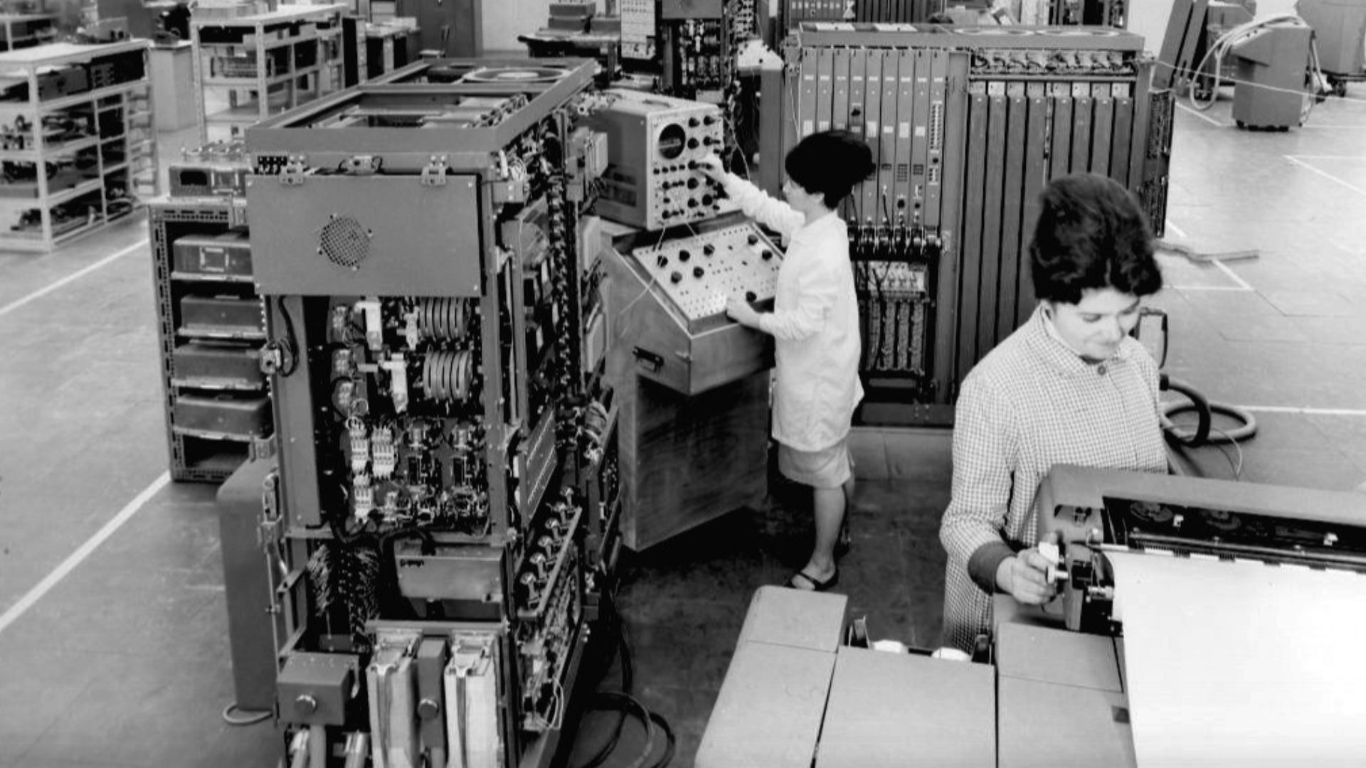 Displayed here are several ET cabinets in the process of assembly, along with the testing of an operator console in the center.