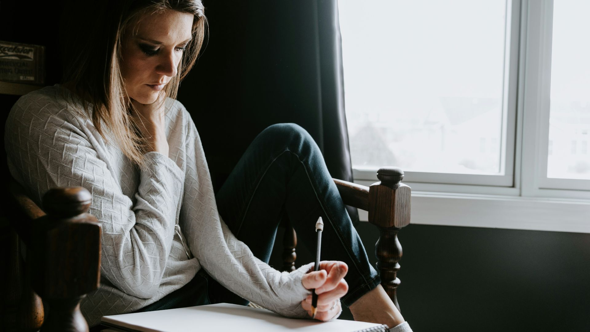 Woman sitting in chair writing in notebook