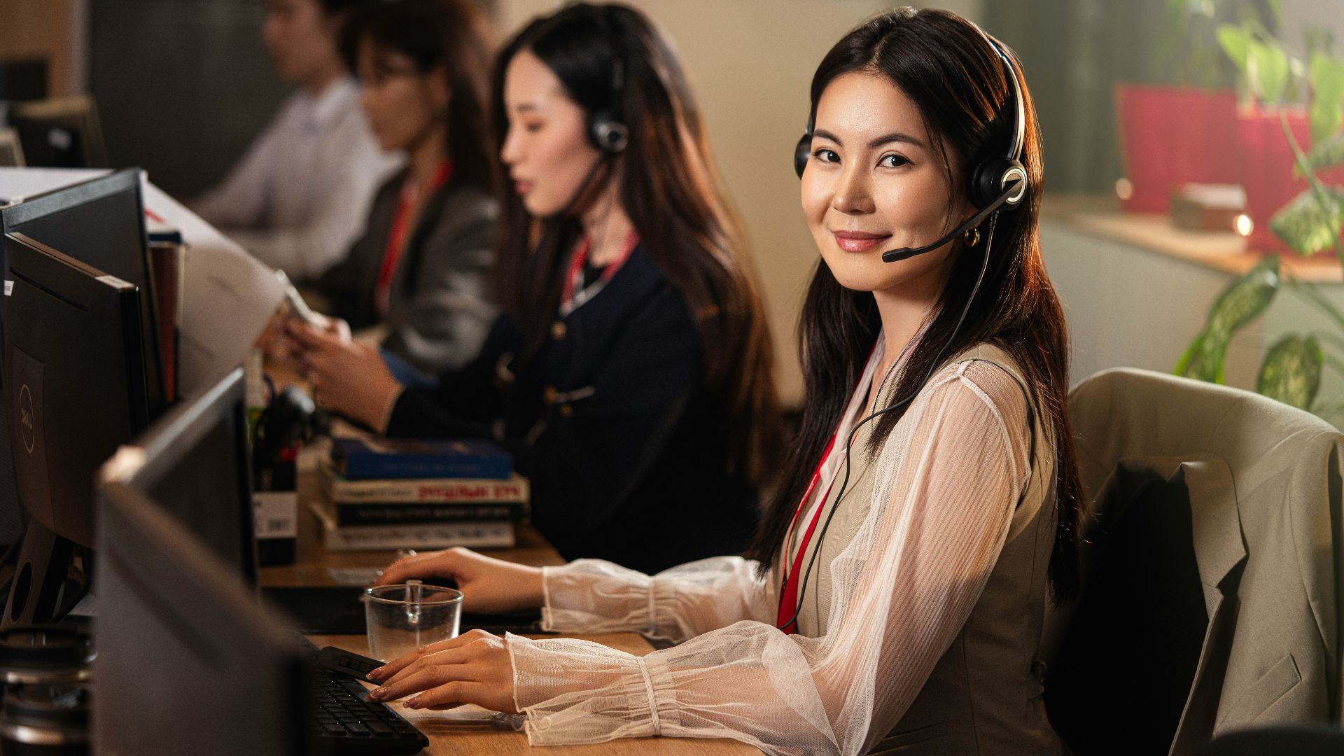A smiling woman wearing a headset at a computer