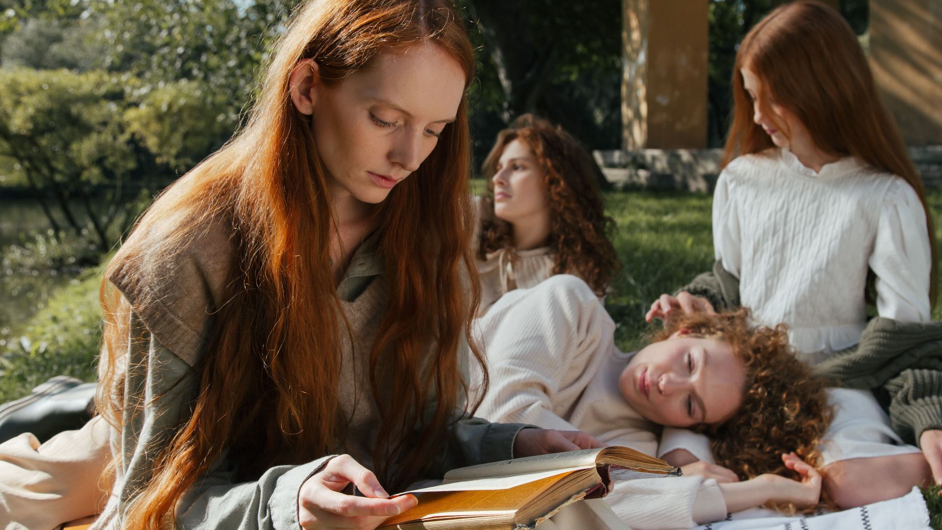 Four women enjoying a peaceful day reading and relaxing outdoors in a park.