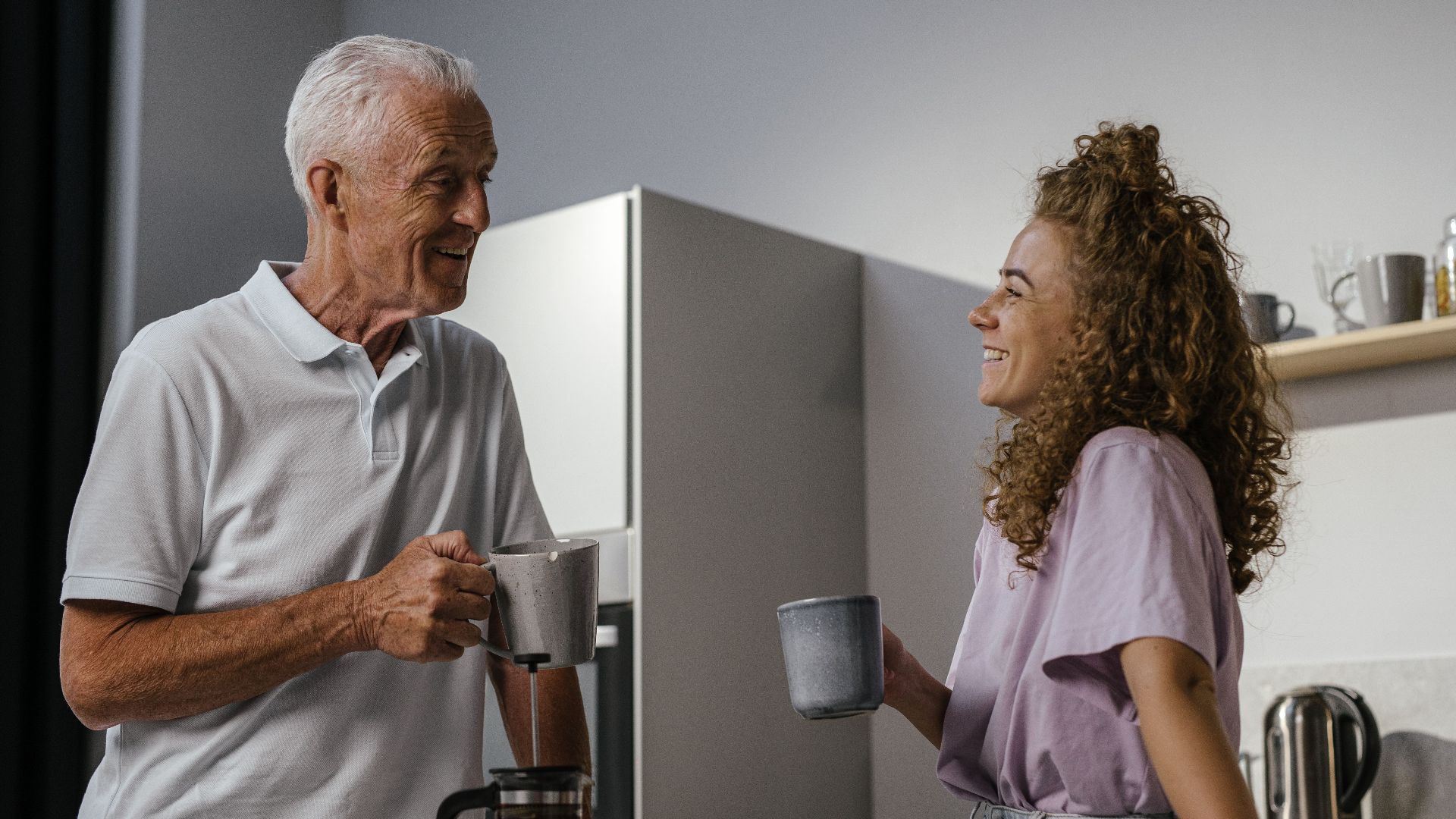 A joyful moment of a grandfather and granddaughter enjoying coffee in a modern kitchen.