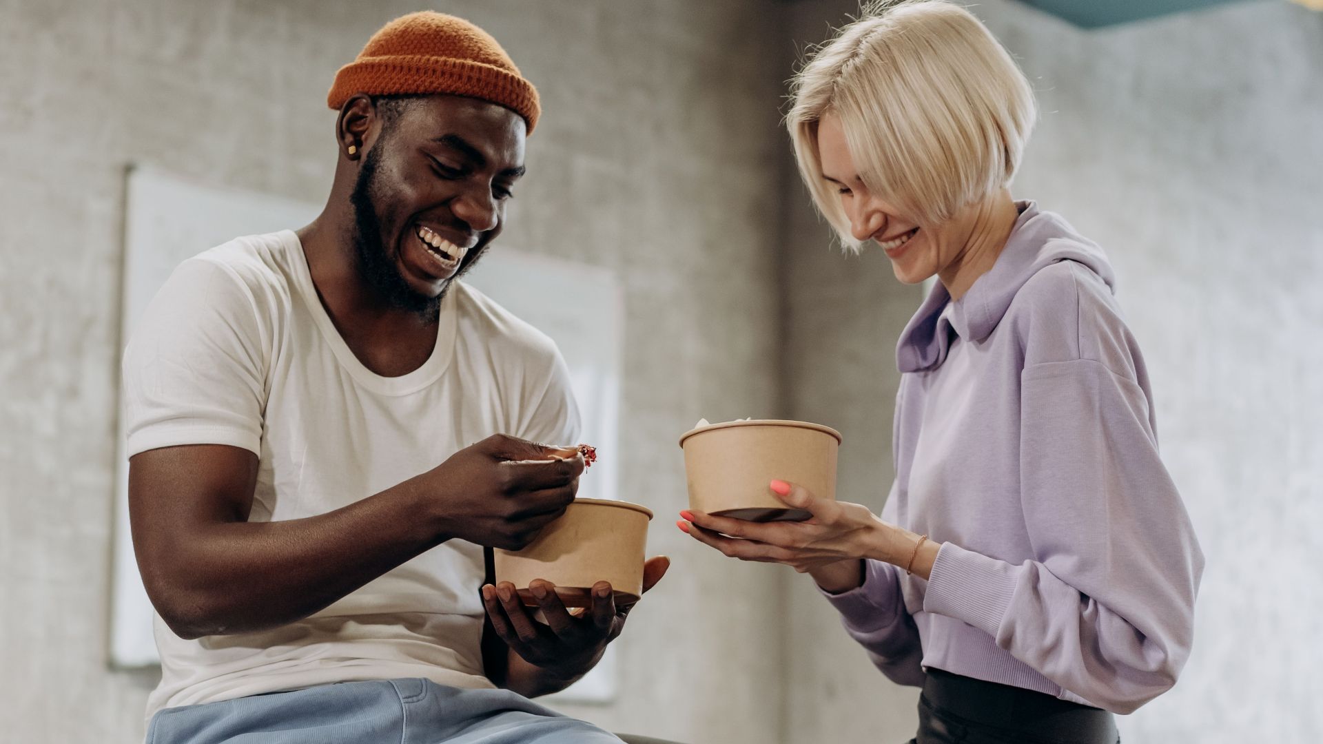 Two friends sharing a joyful moment while enjoying a healthy meal indoors.