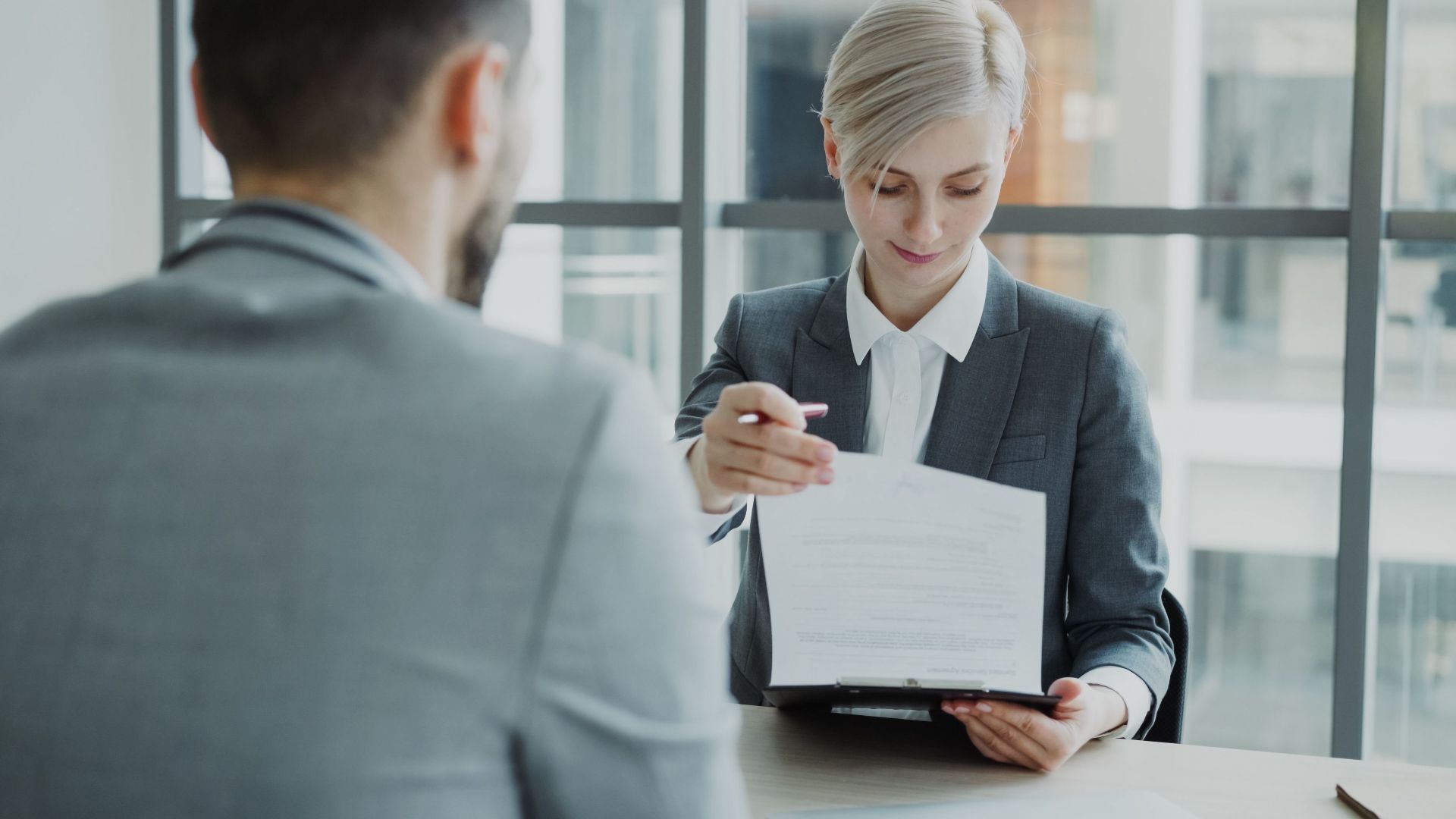 Business professionals reviewing a contract in a modern office setting.