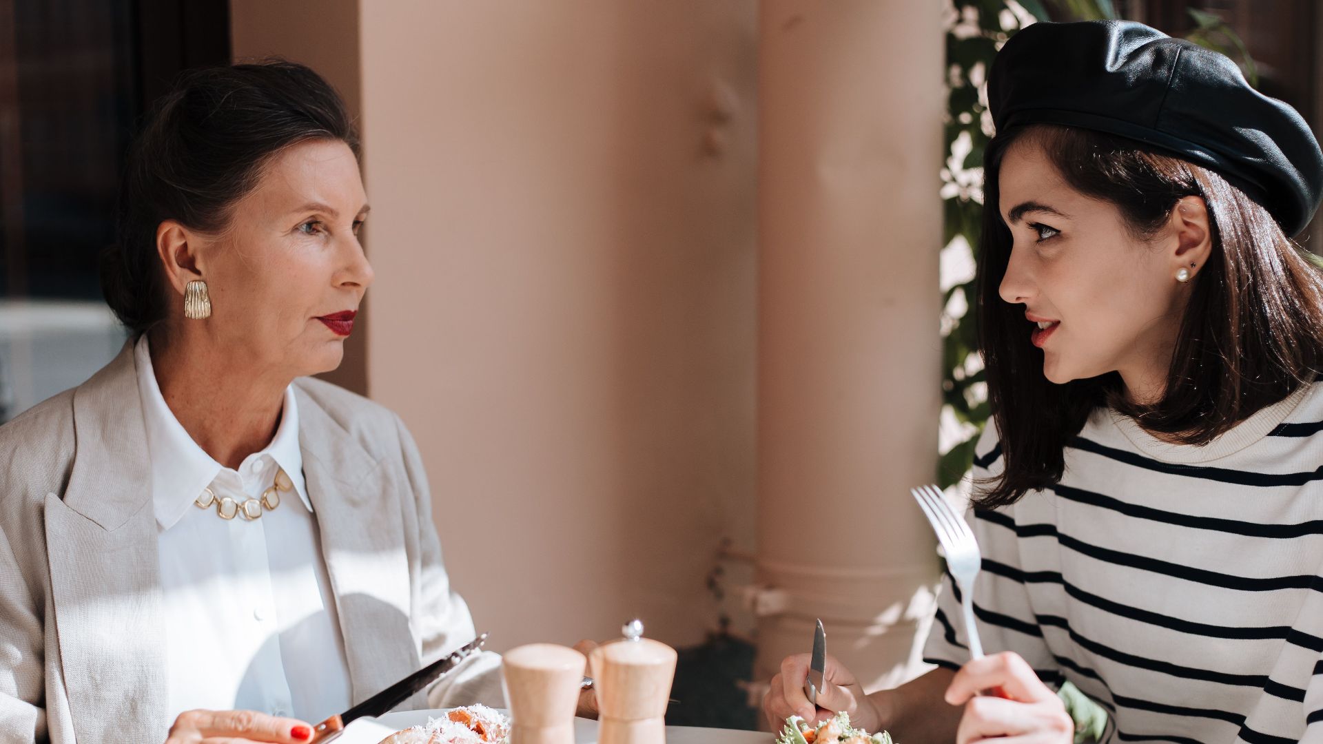 Elegant women enjoying a meal at an outdoor cafe. Fashionable style and serene atmosphere.