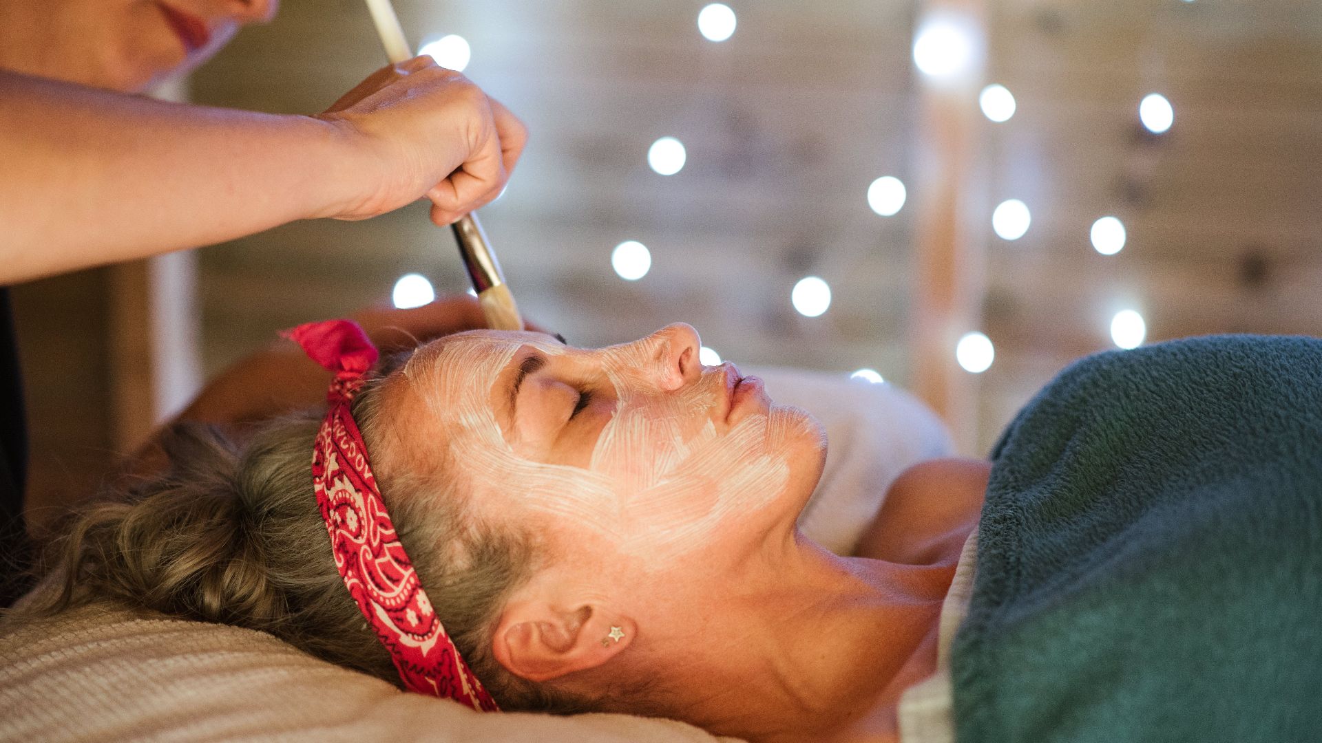 Adult lady cleaning face with mask and brush in spa center from cosmetician