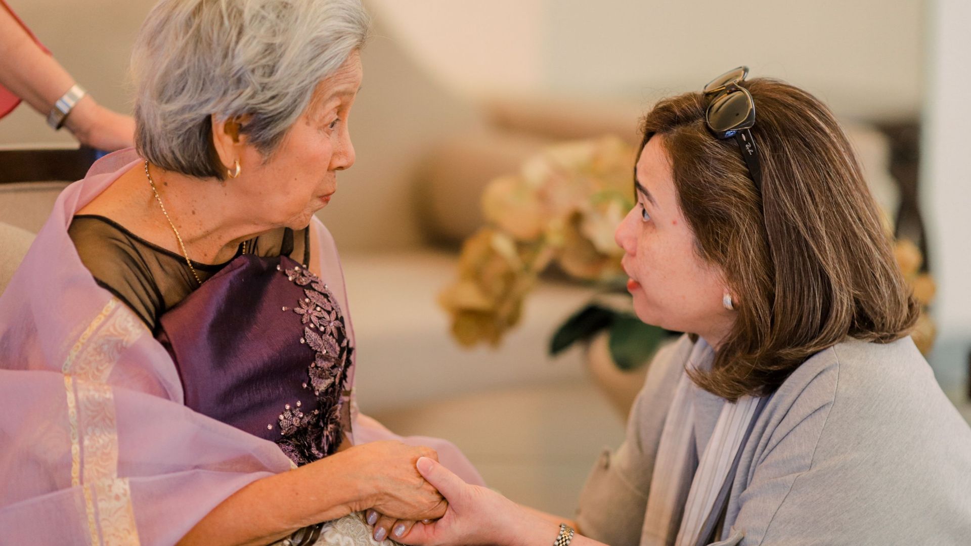 Heartwarming interaction between a senior woman and her adult daughter indoors.