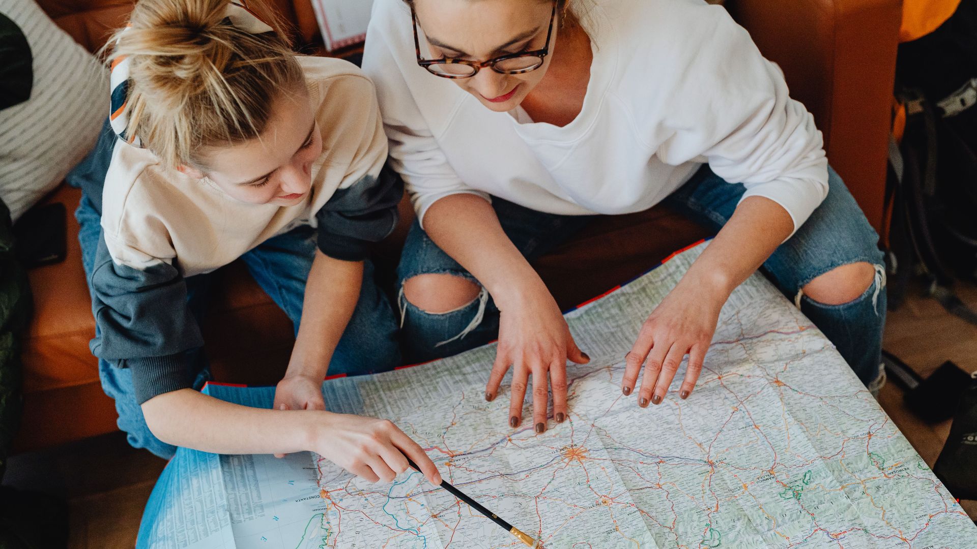 A mother and daughter plan their journey using a map, symbolizing adventure and bonding.
