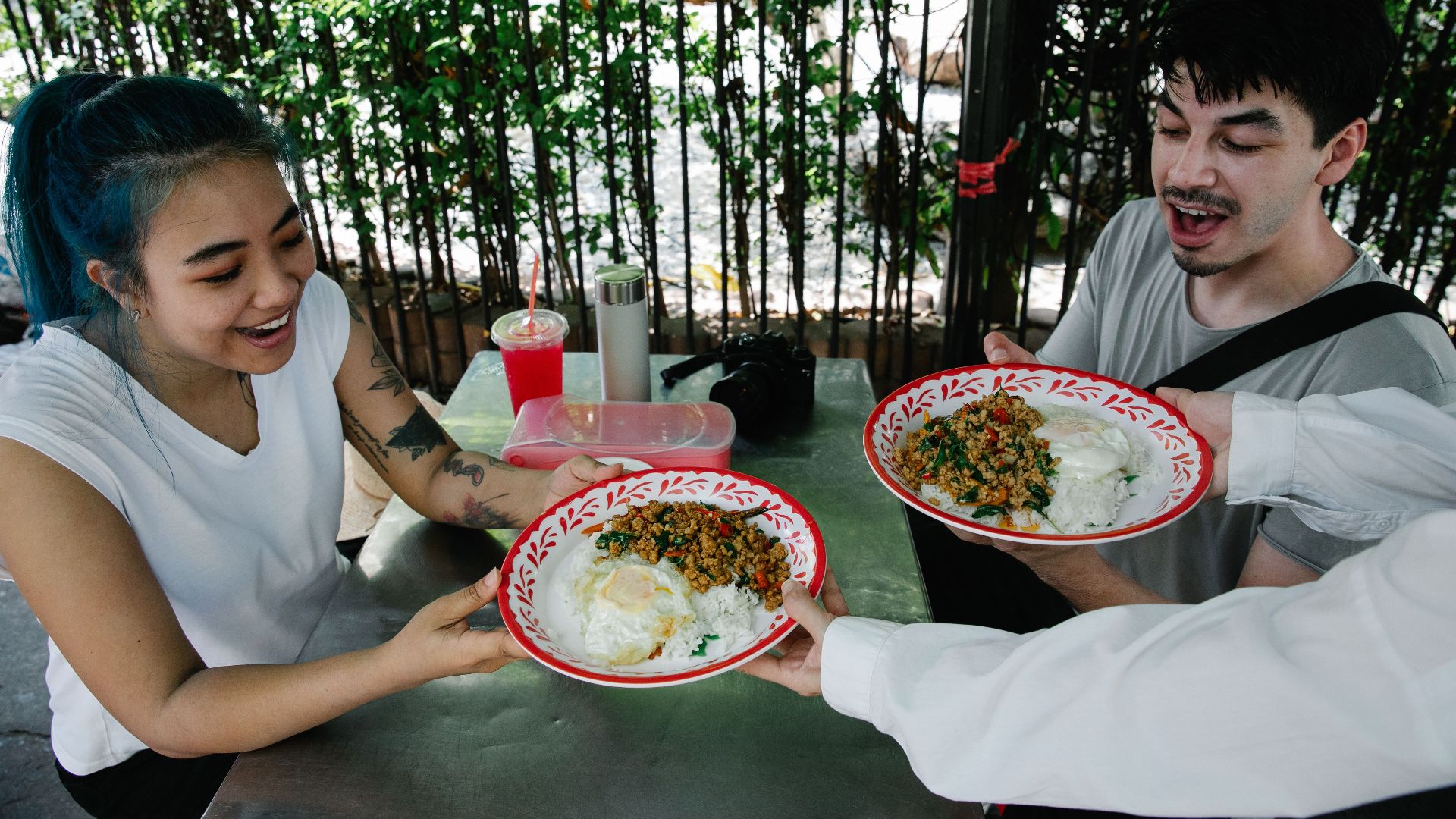 Two friends excitement as they receive delicious Thai dishes served outdoors.