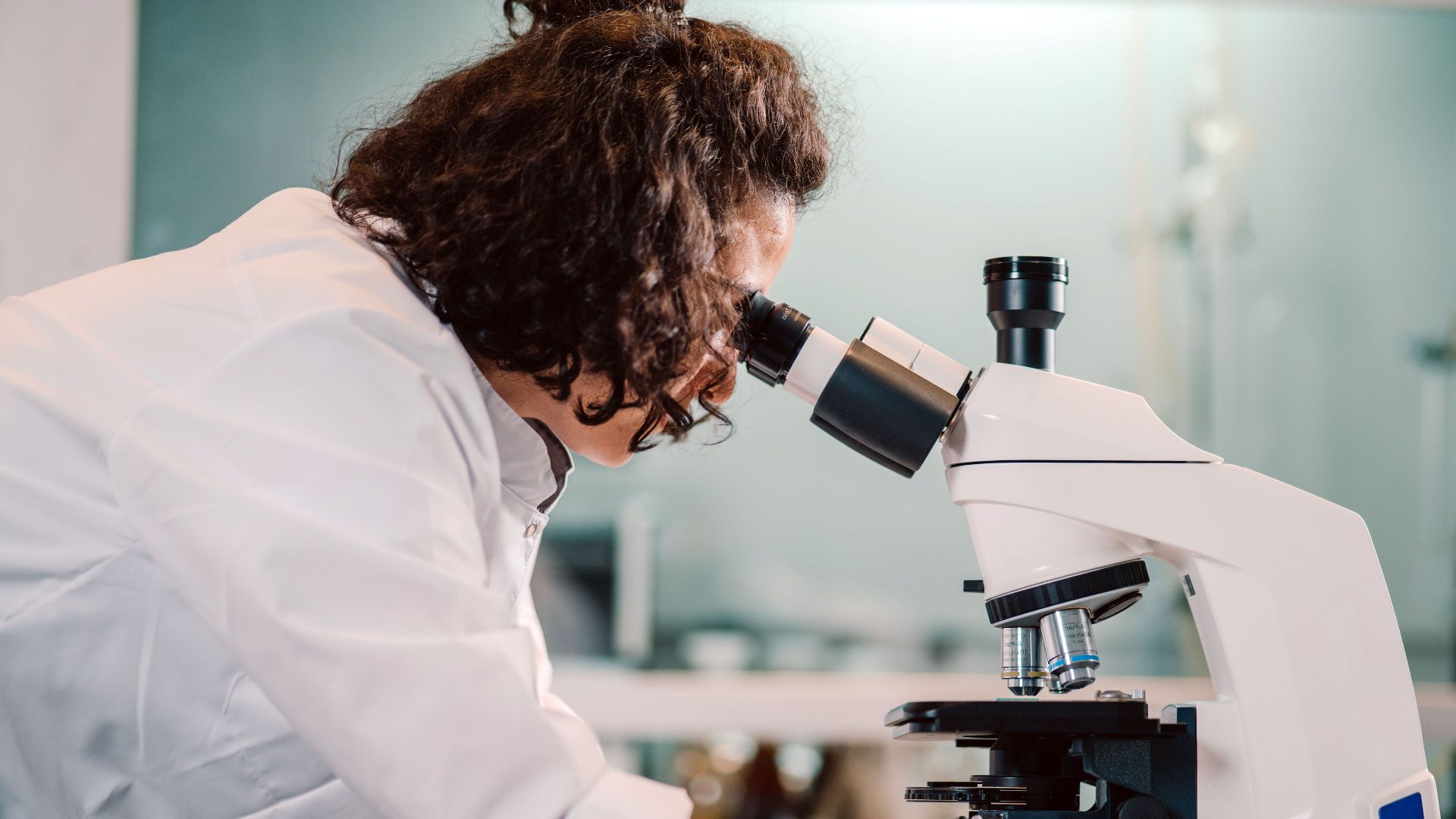 A woman scientist using a microscope in a laboratory setting.