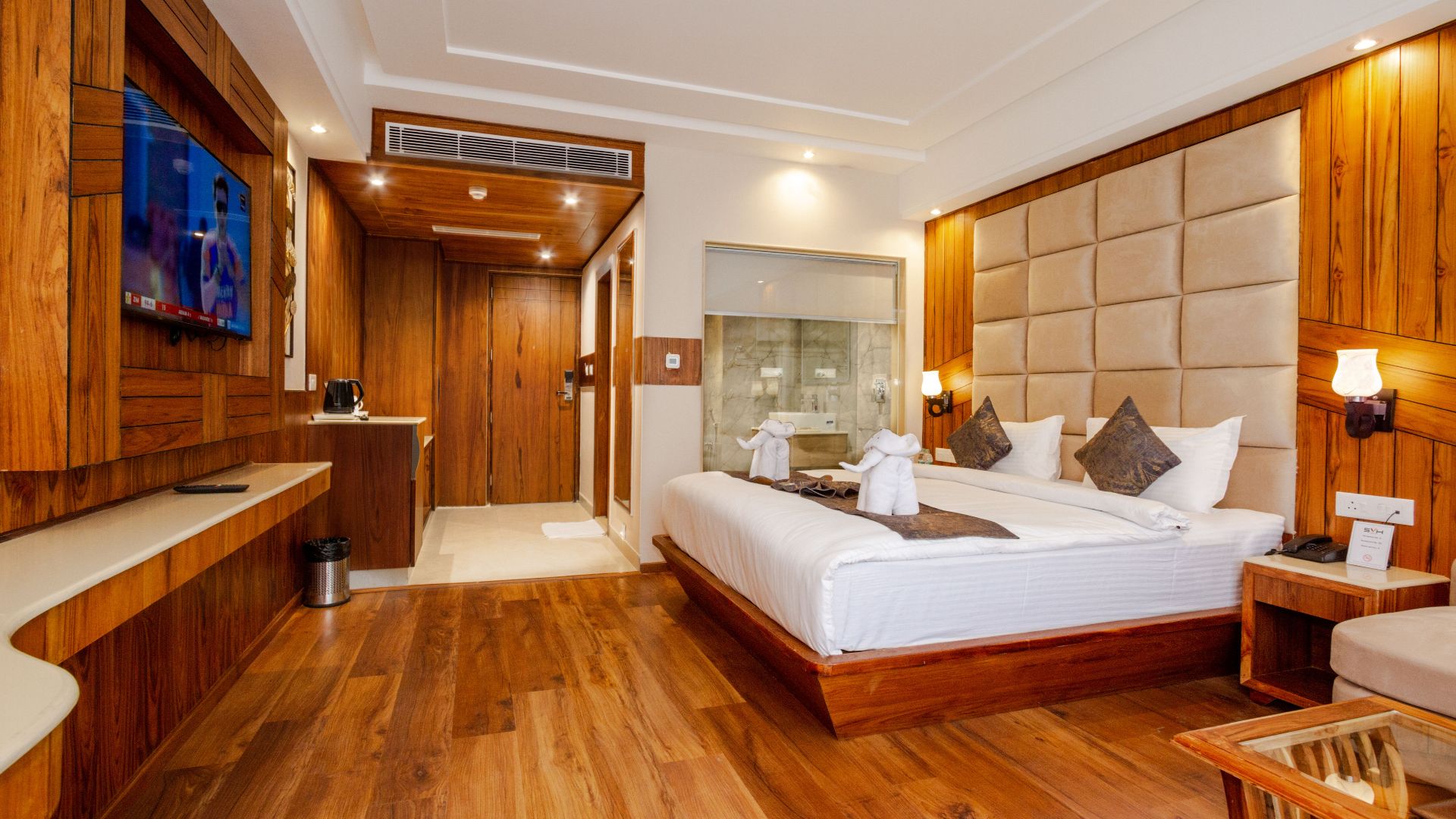 Elegant hotel room featuring wooden decor, a plush bed, and contemporary interior design.