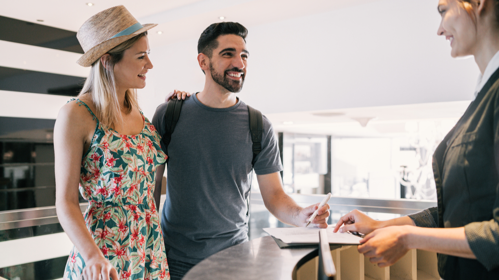 couple doing check-in at hotel reception front desk
