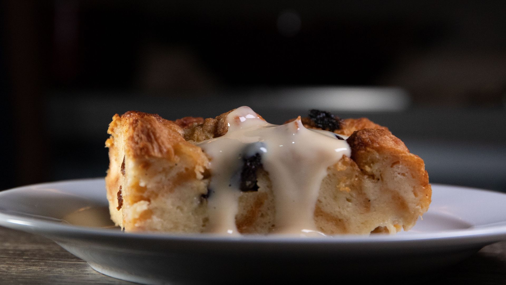 A slice of delicious bread pudding topped with creamy vanilla sauce, ideal for dessert lovers.