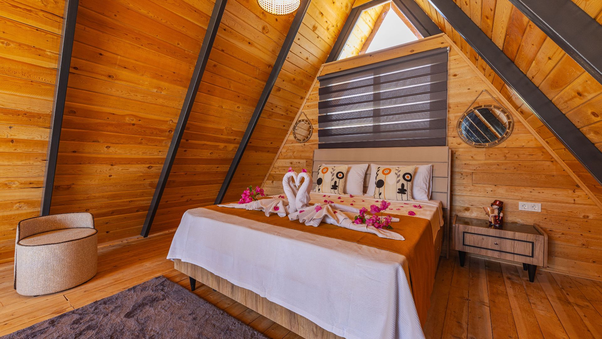 A charming wooden bedroom featuring towel swans and rose petals, ideal for romantic getaways.