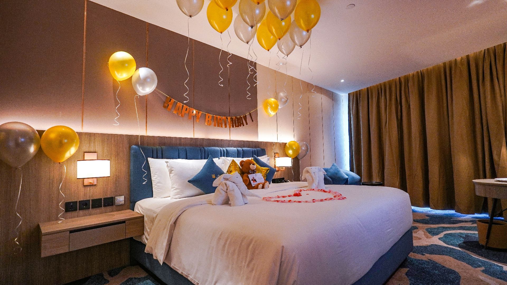 a bedroom with balloons and a bed with a teddy bear on it