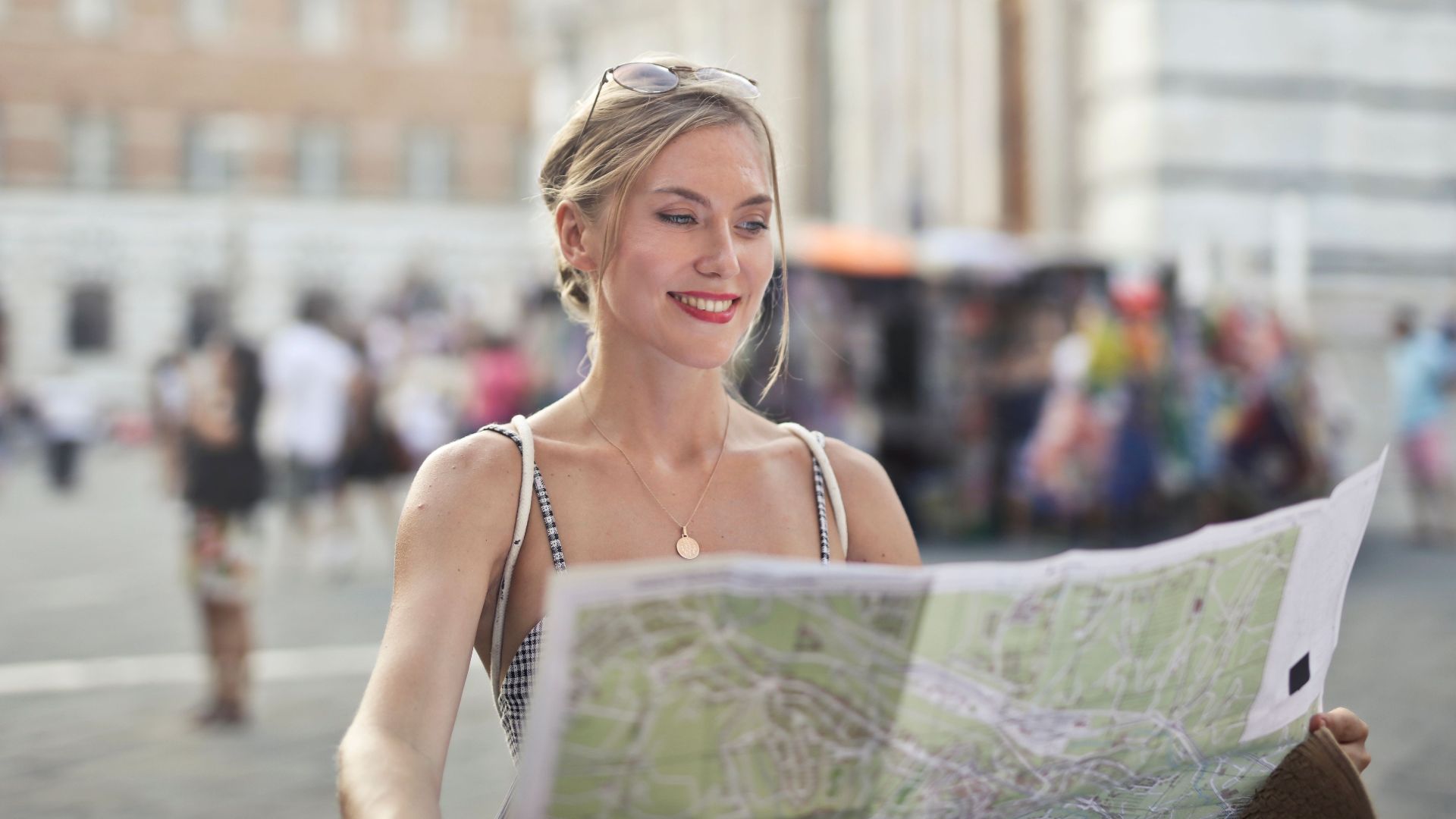 Smiling woman holding a map, discovering city landmarks under the sun. Perfect for travel and tourism concepts.