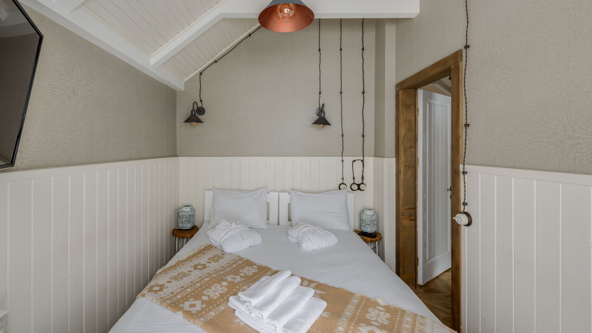 A serene Scandinavian-style bedroom featuring minimal decor and modern pendant lights.
