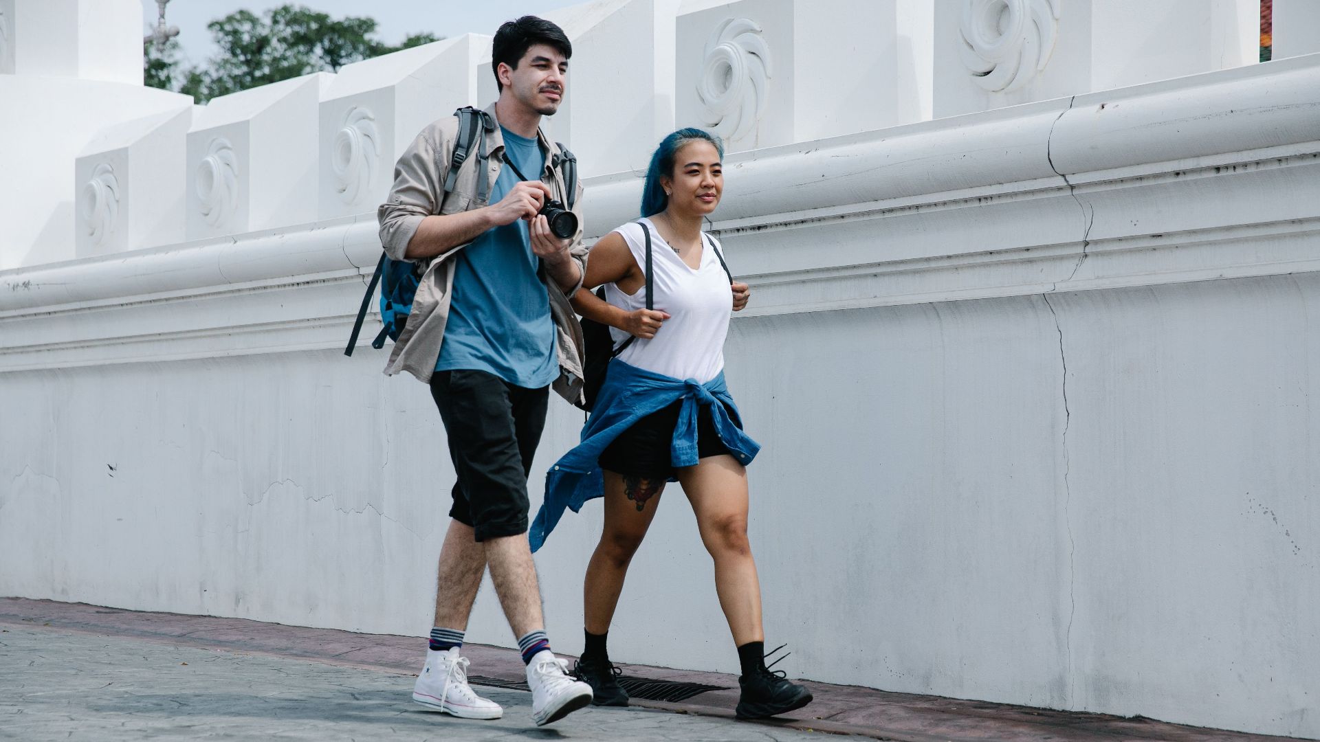 A couple enjoys a city walk together, capturing moments with a camera.