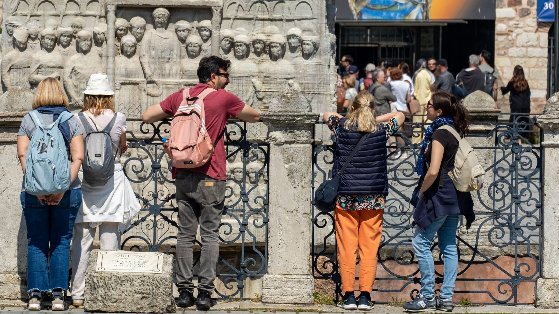 Visitors engage with an ancient stone monument in Istanbul on a sunny day.