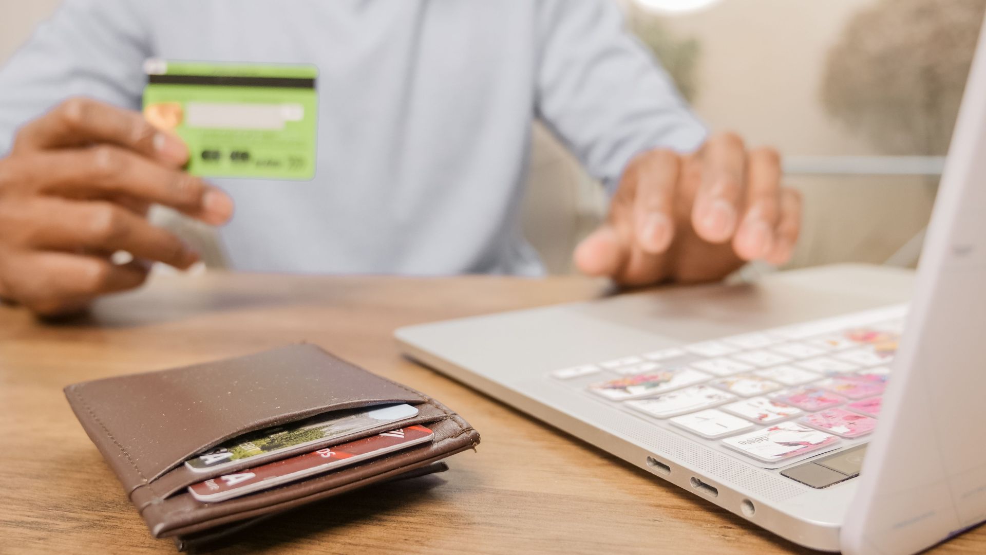 Close-up of hands with a bank card and laptop for online shopping. Perfect for illustrating e-commerce concepts.