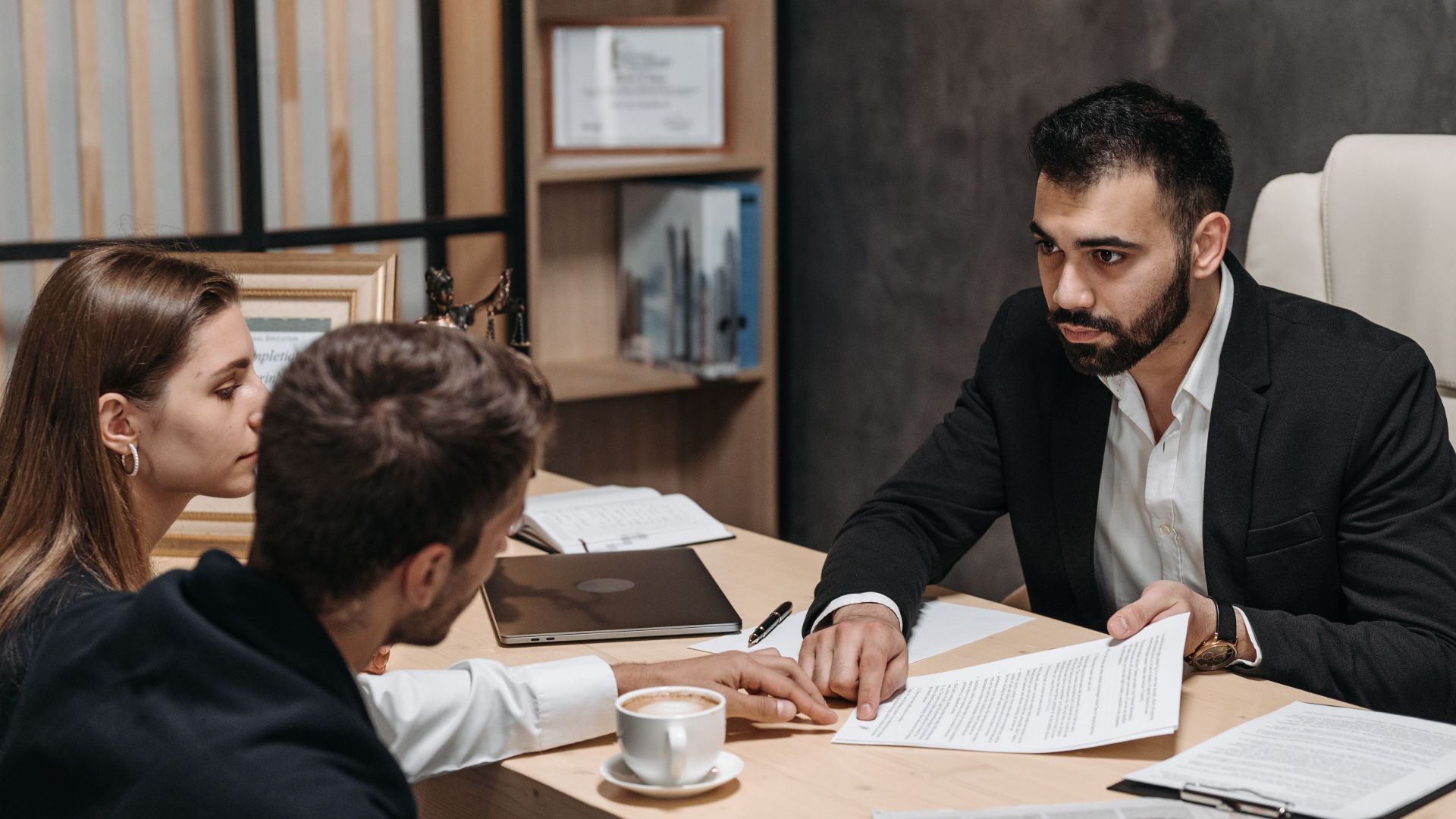 Lawyer discussing legal documents with clients at office desk.