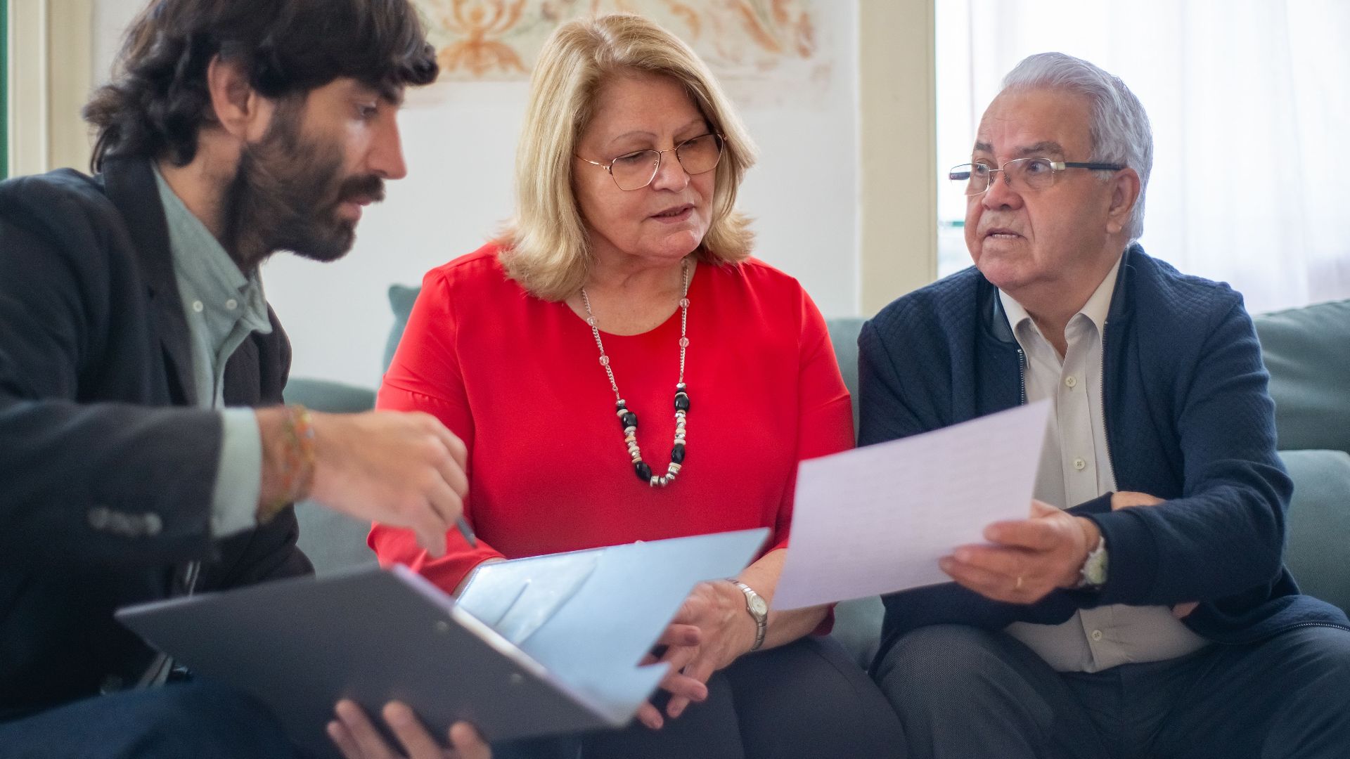 Senior couple consulting with a professional advisor, discussing documents indoors.