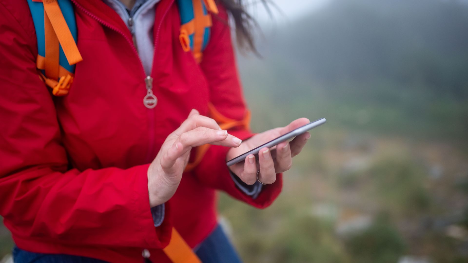 Close-up of a hiker in Portugal using a smartphone outdoors on a foggy day.