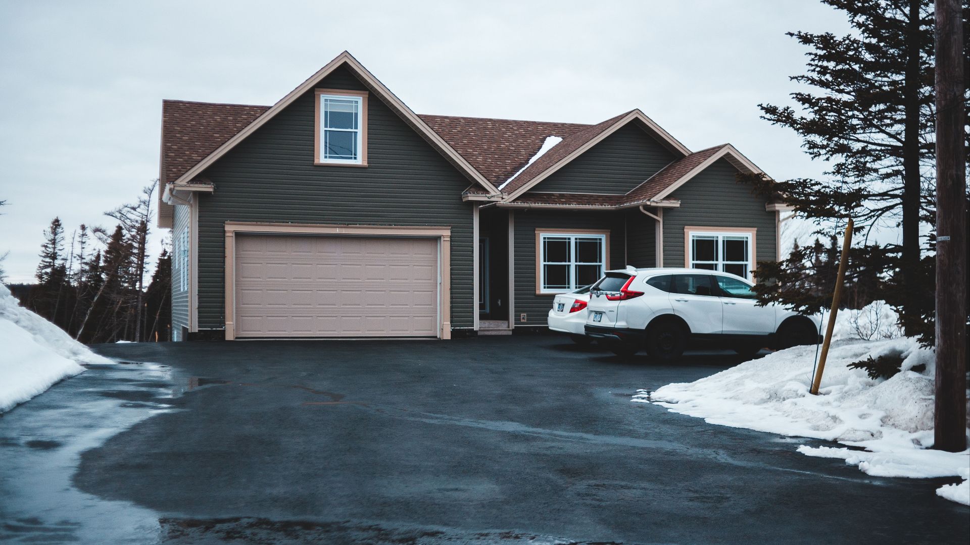 Exterior of small residential house in neighbourhood with cars parking on snowy ground in misty day