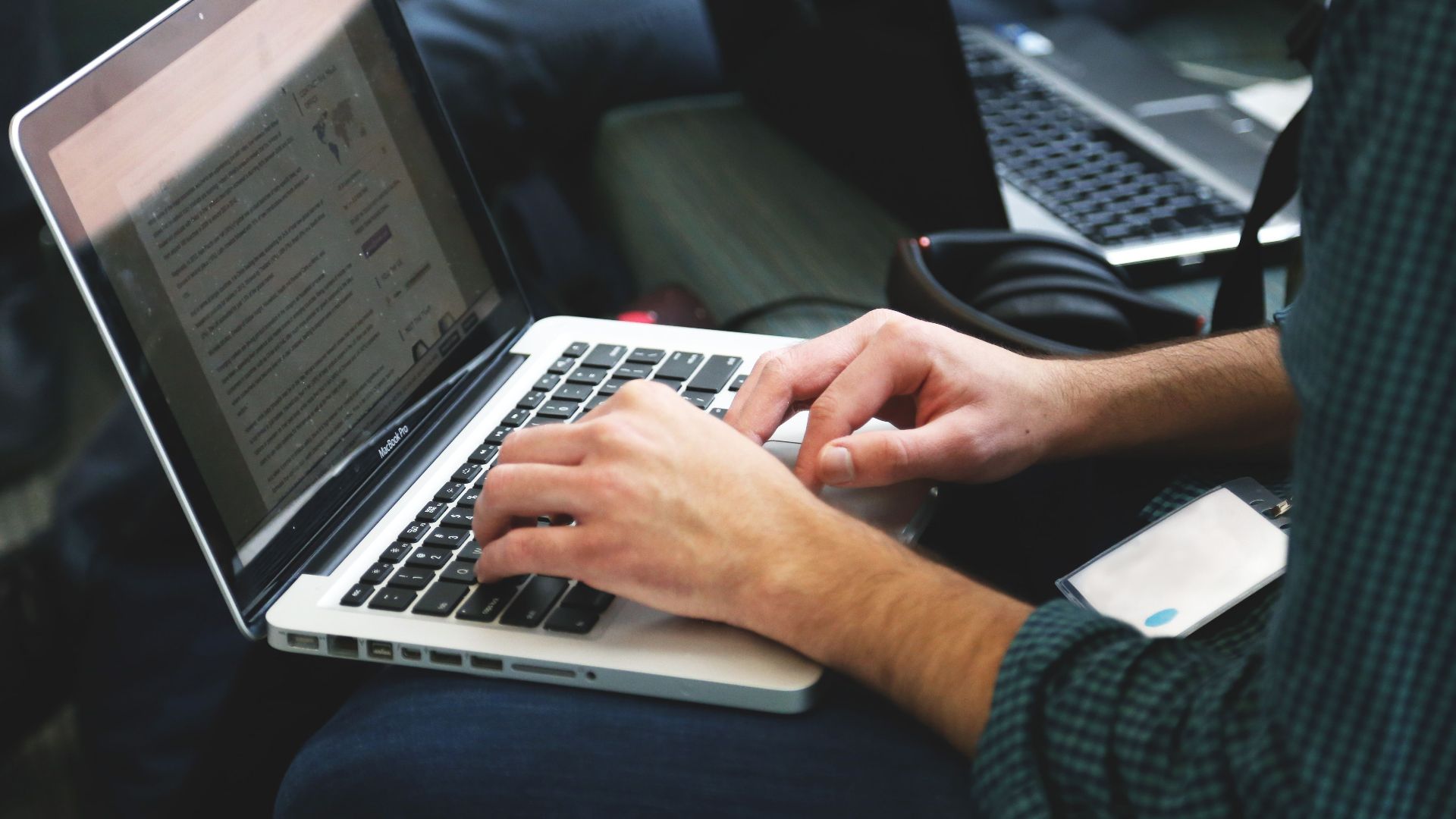 A programmer typing on a laptop in an indoor setting, showcasing technology in use.