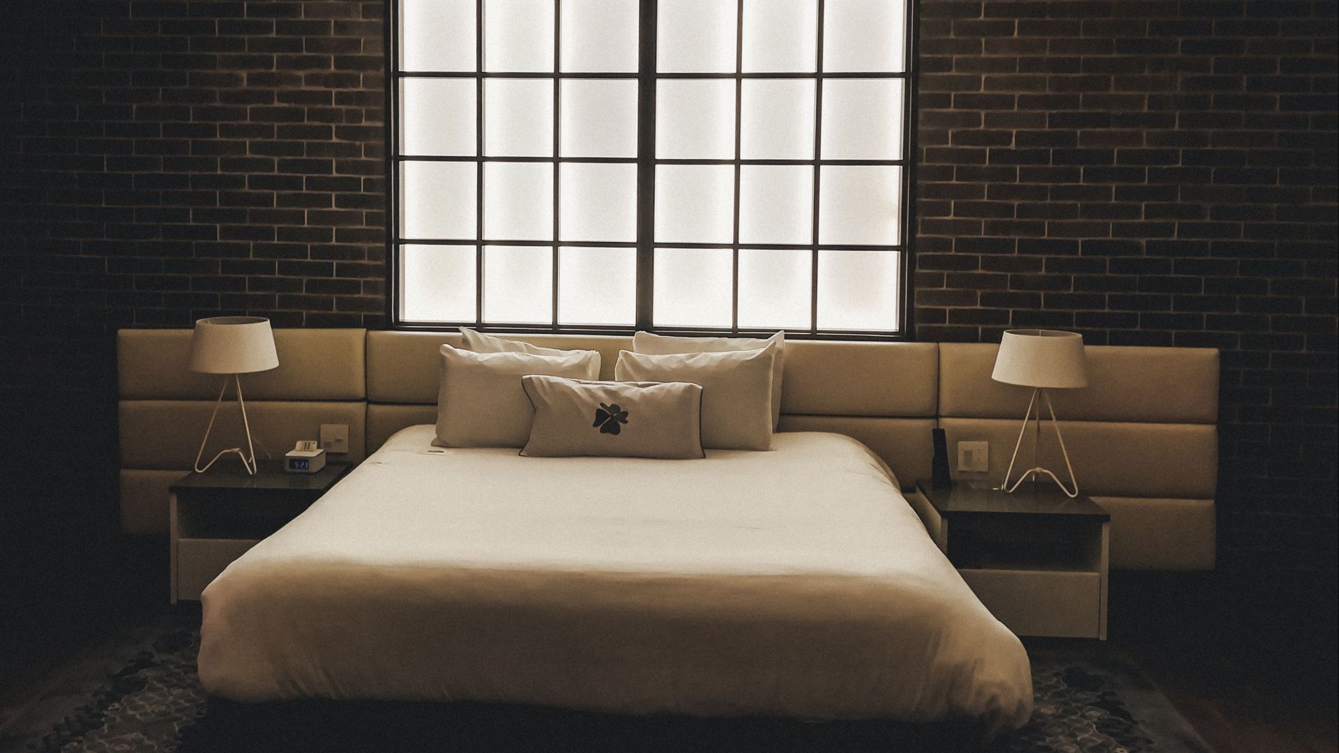Stylish bedroom featuring a brick wall, modern design, and ambient lighting.