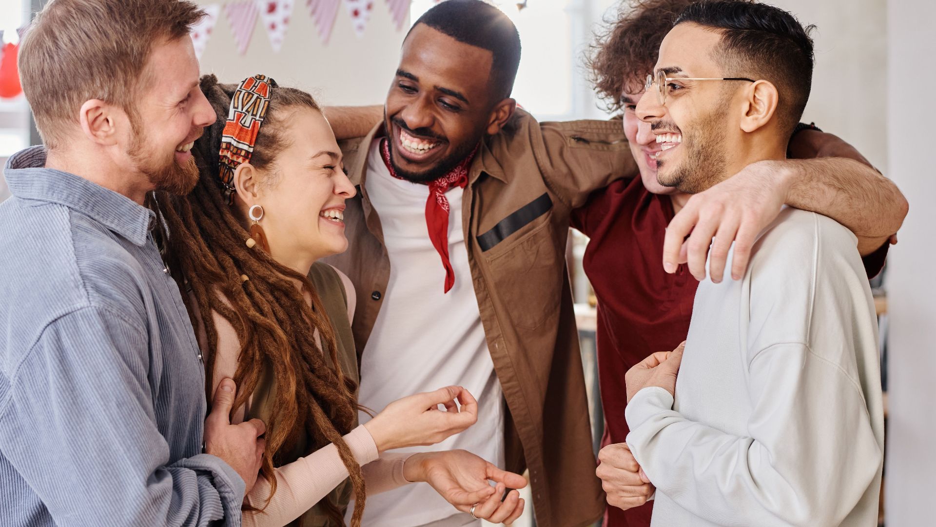 A joyful group of diverse friends celebrates indoors, embodying unity and happiness.