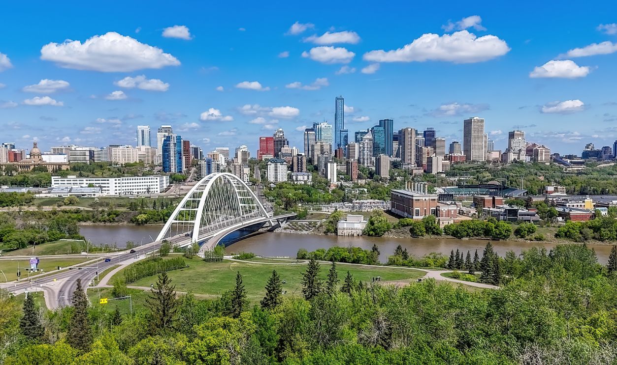 Edmonton, Alberta, Canada. May 20, 2025. Edmonton's dynamic skyline and iconic Walterdale Bridge span the North Saskatchewan River, framed by lush river valley greenery under a vibrant sky.